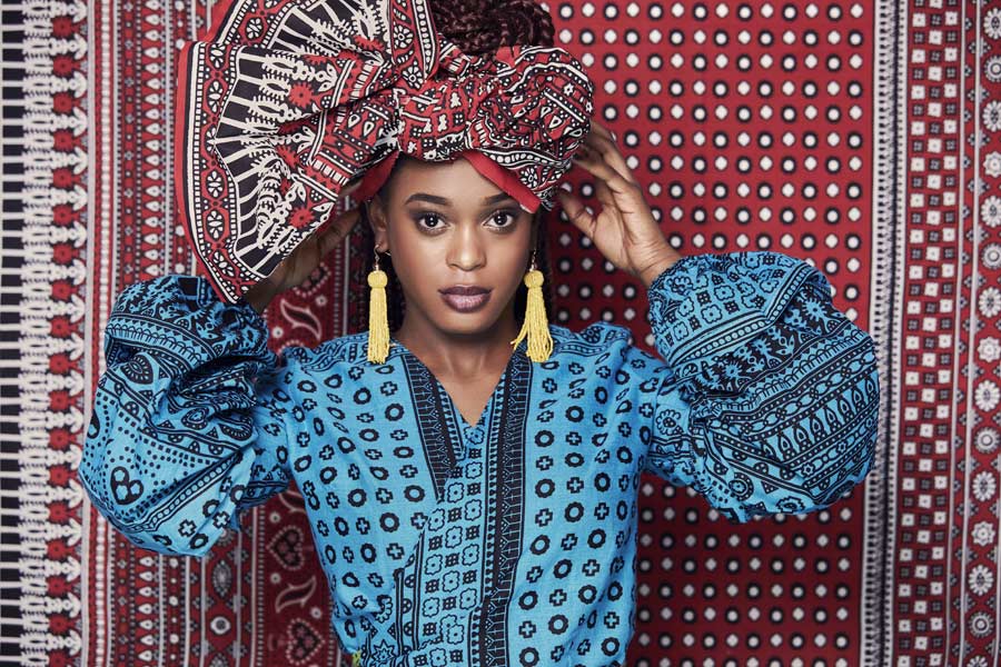 dunkelhäutige Frau in afrikanischer Kleidung vor afrikanischem Tuch
