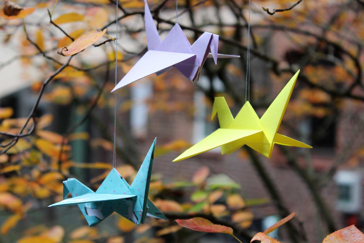 Kraniche aus Origamipapier in einem herbstlichen Busch, groß
